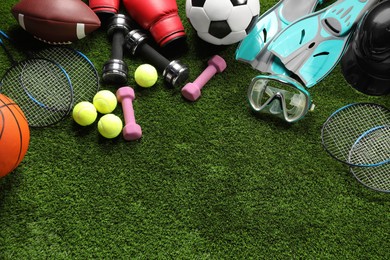 Photo of Different sports equipment on artificial grass, flat lay. Space for text