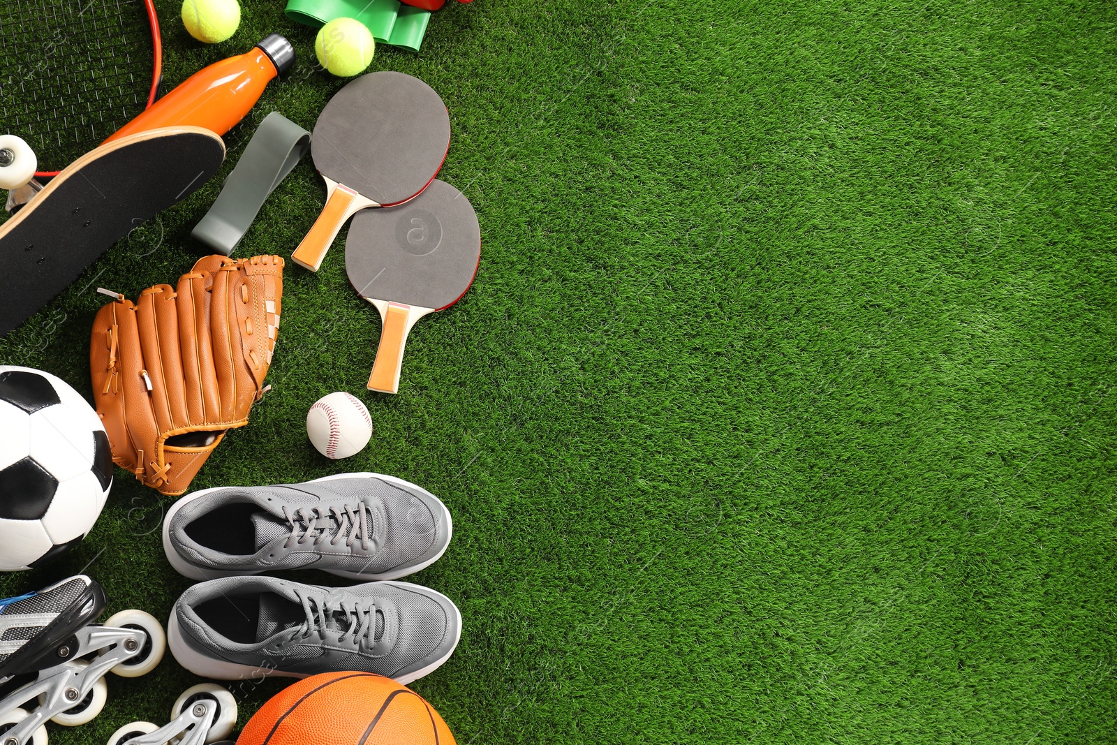 Photo of Different sport equipment on artificial grass, flat lay. Space for text