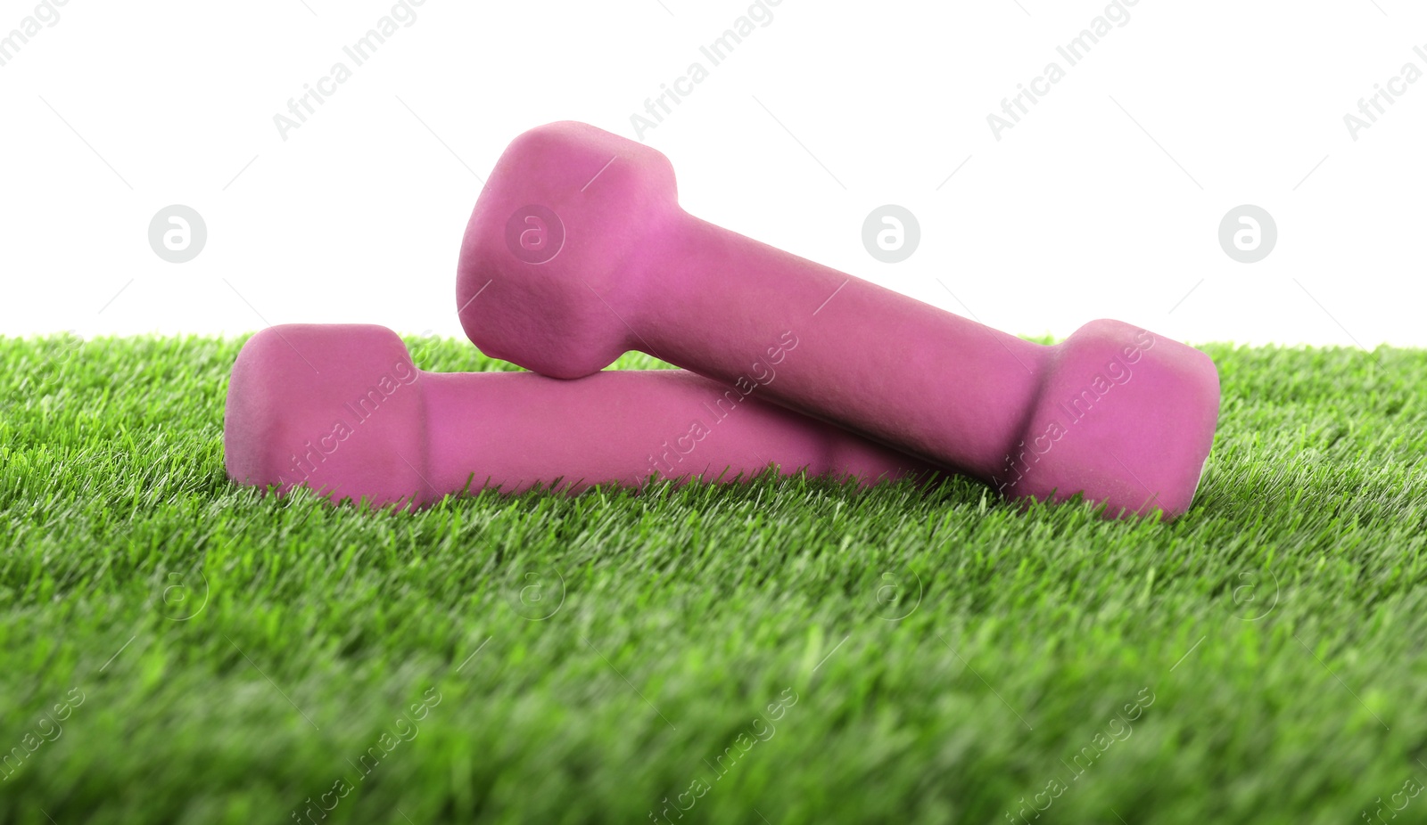 Photo of Dumbbells on artificial grass isolated on white. Sport equipment