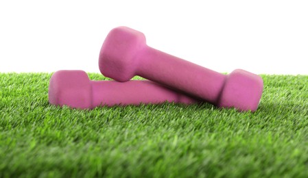 Photo of Dumbbells on artificial grass isolated on white. Sport equipment