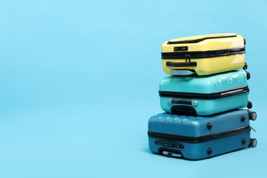 Photo of Stack of colorful suitcases on light blue background. Space for text