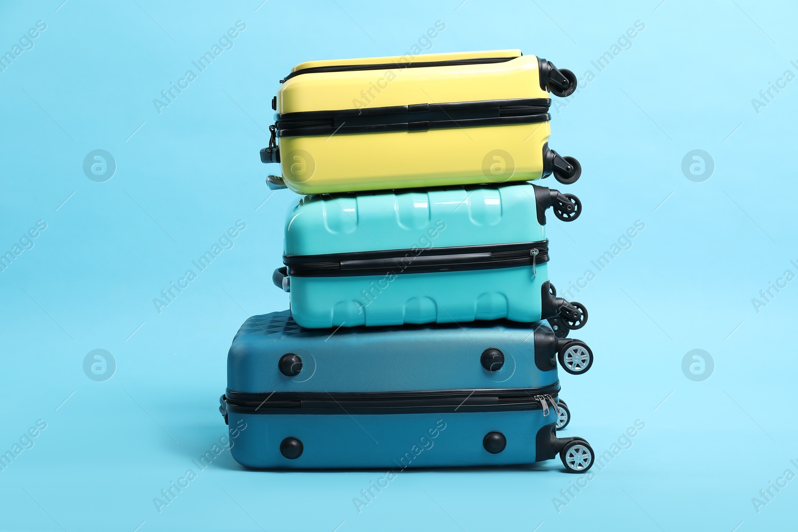 Photo of Stack of colorful suitcases on light blue background