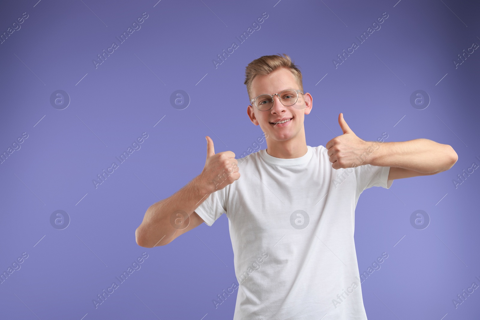 Photo of Happy man showing thumbs up on purple background, space for text. Like gesture