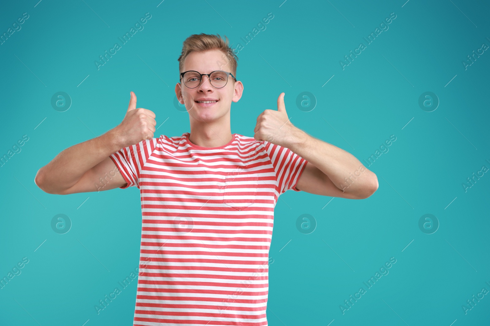 Photo of Happy man showing thumbs up on light blue background. Like gesture