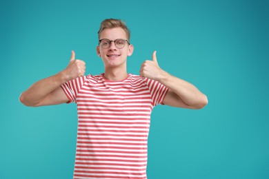 Photo of Happy man showing thumbs up on light blue background. Like gesture