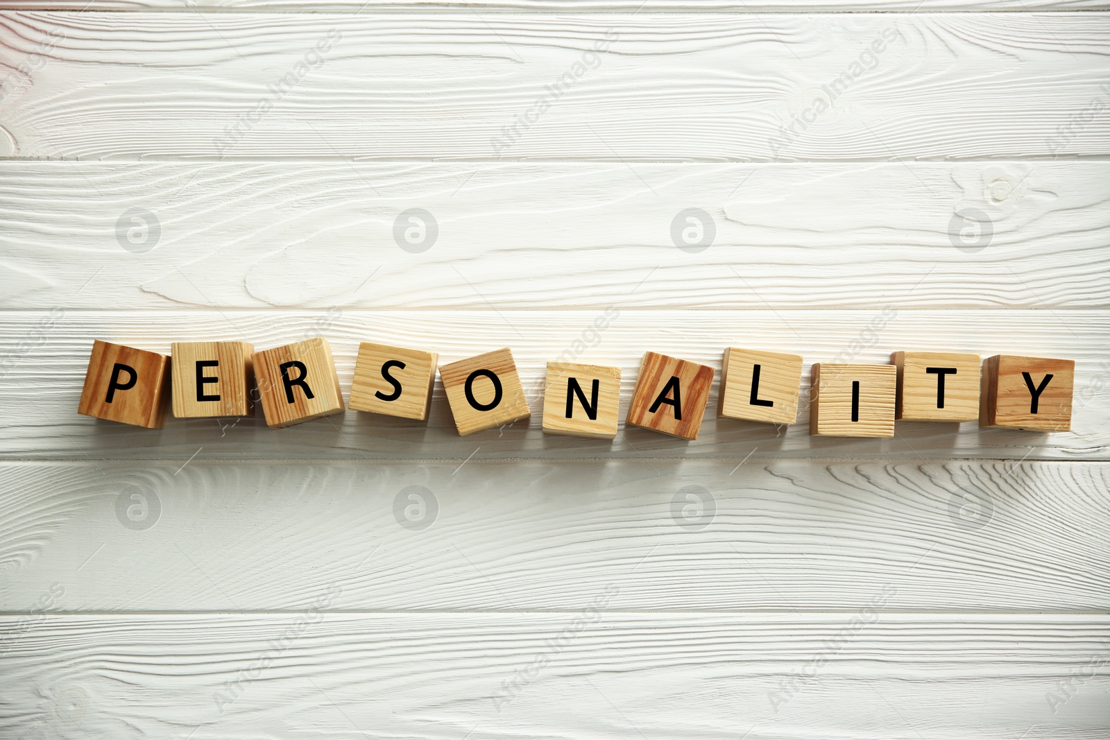 Photo of Word Personality made of cubes with letters on white wooden table, top view