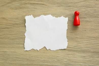 Photo of Blank note and game piece on wooden table, top view. Space for text