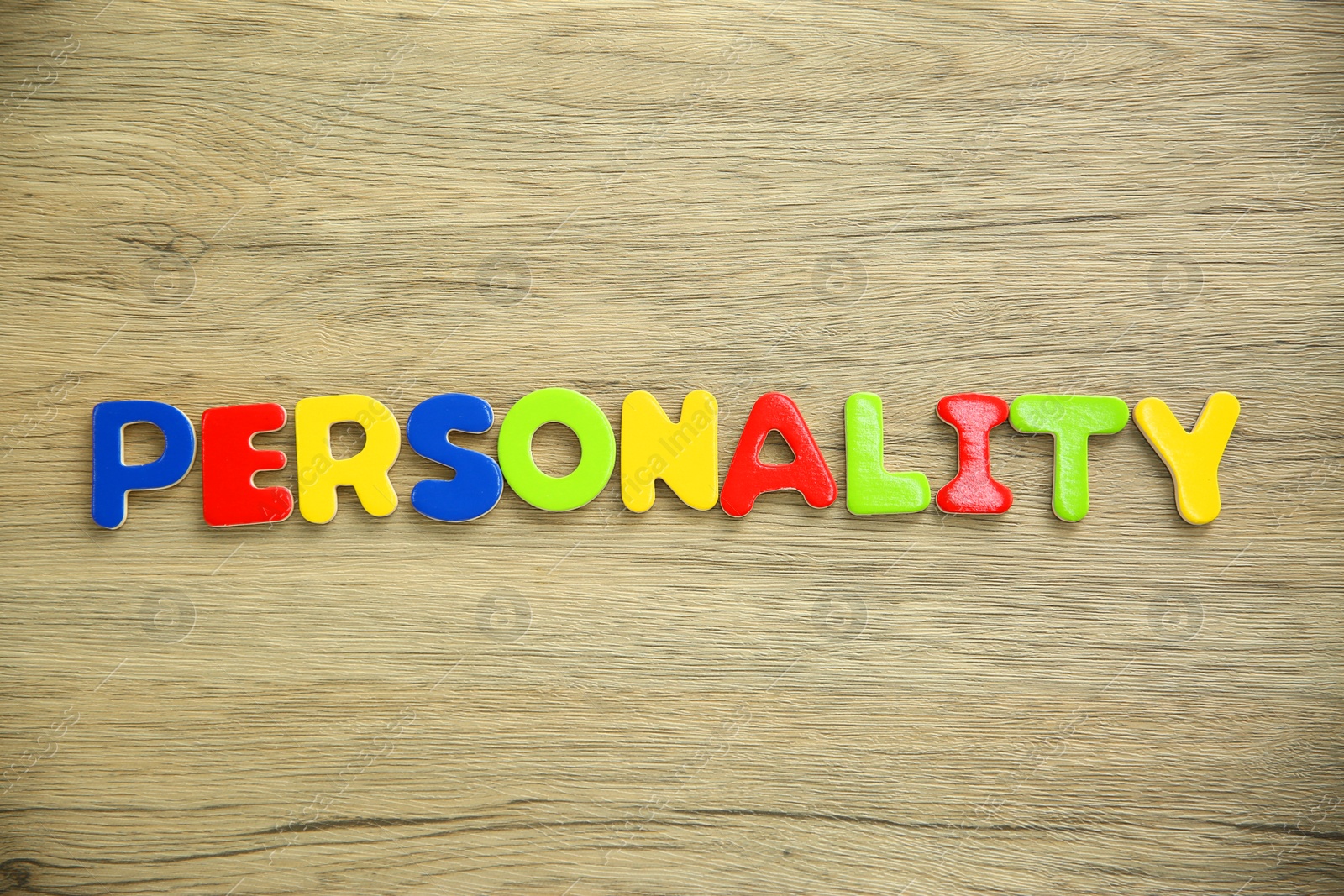 Photo of Word Personality made of colorful letters on wooden table, top view