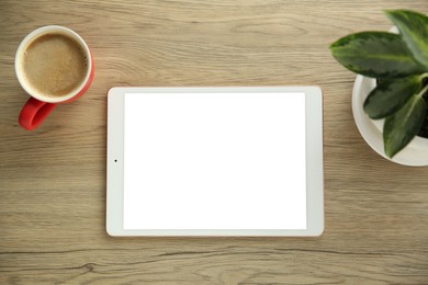 Photo of Tablet with blank screen, coffee and houseplant on wooden table, top view. Space for design