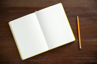 Photo of Blank notebook and pencil on wooden table, top view. Space for text