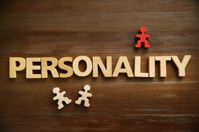 Photo of Word Personality made of letters and human figures on wooden table, top view