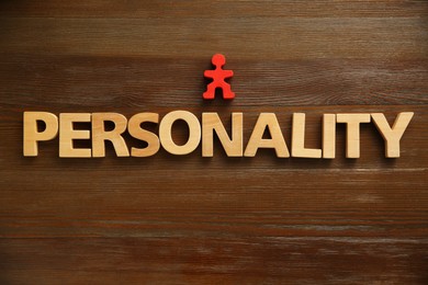 Photo of Word Personality made of letters and human figure on wooden table, top view