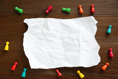 Photo of Blank note and game pieces on wooden table, flat lay. Space for text