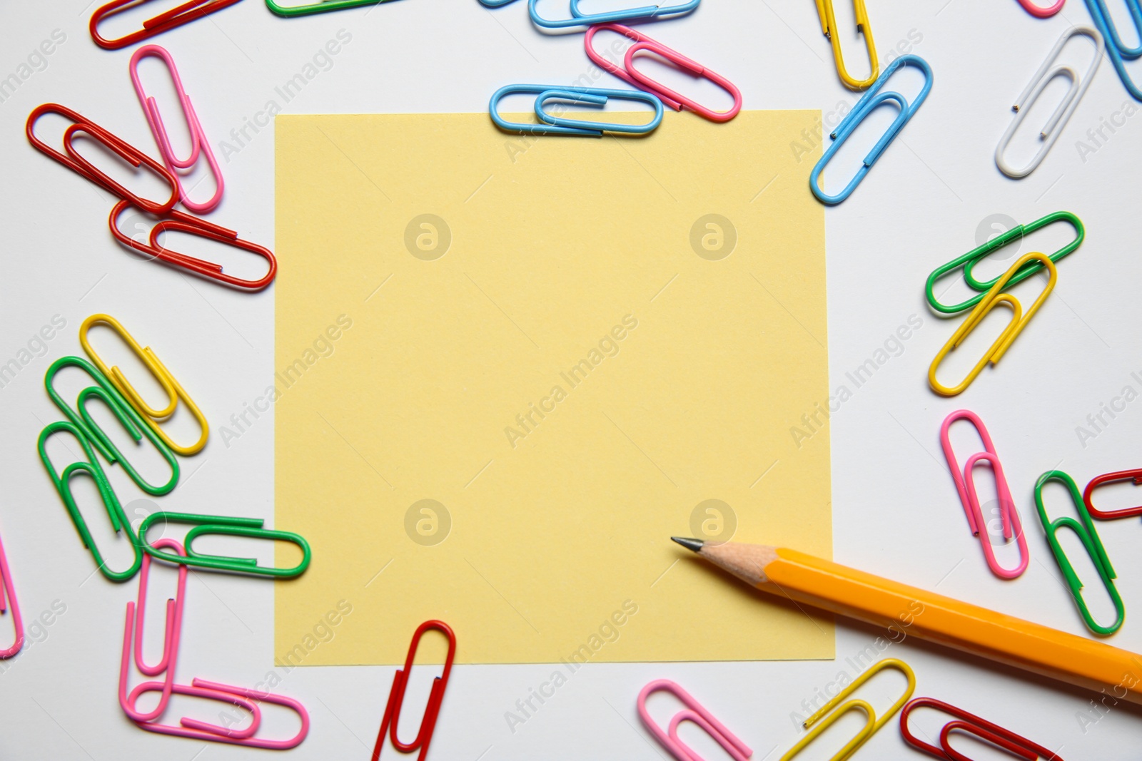 Photo of Blank note, paper clips and pencil on white background, flat lay. Space for text