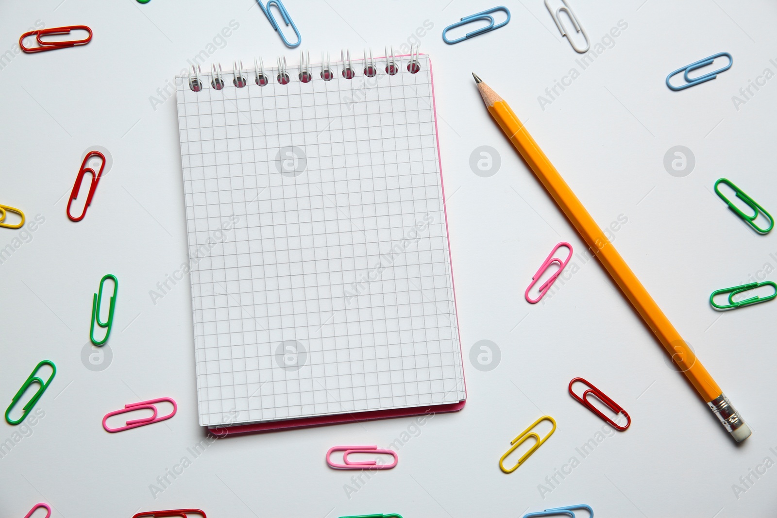 Photo of Blank notebook, paper clips and pencil on white background, flat lay. Space for text