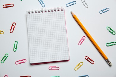 Photo of Blank notebook, paper clips and pencil on white background, flat lay. Space for text