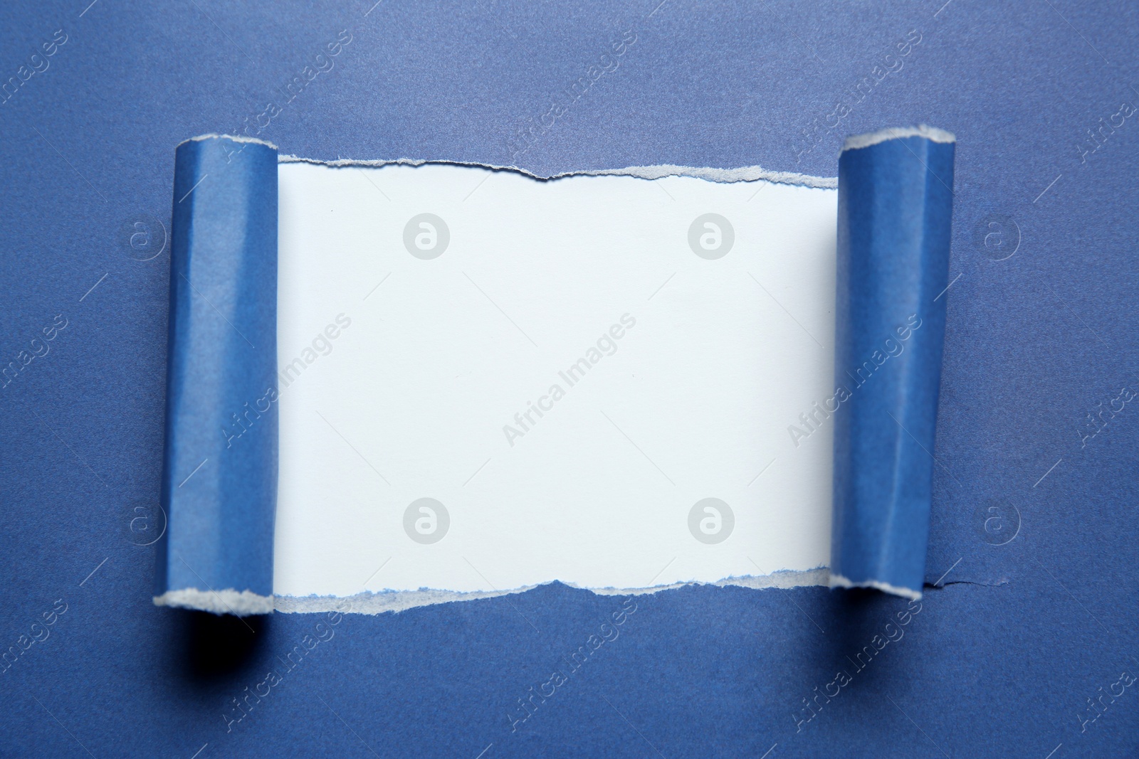 Photo of Blue paper with torn hole on white background, top view. Space for text