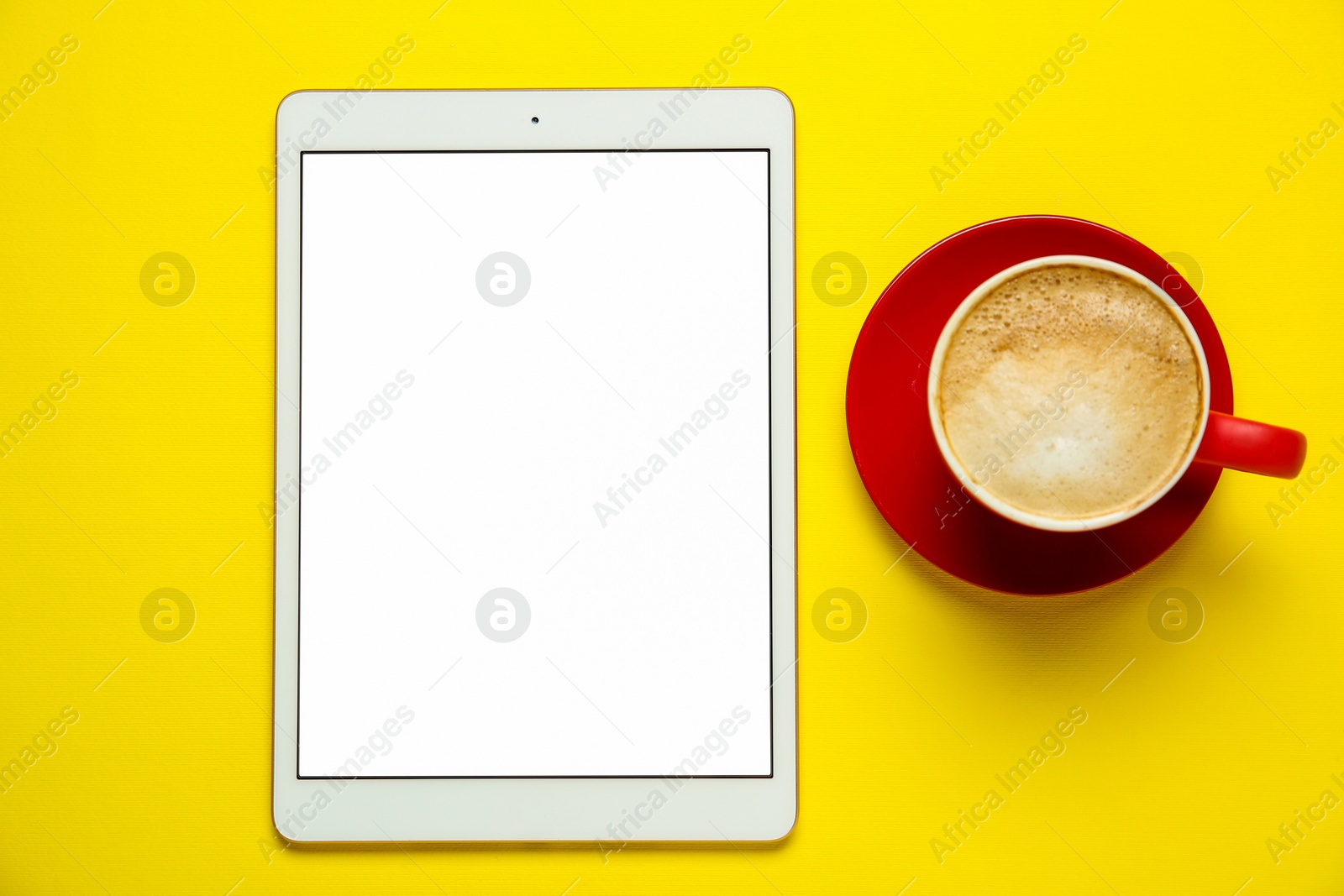 Photo of Tablet with blank screen and coffee on yellow background, top view. Space for design