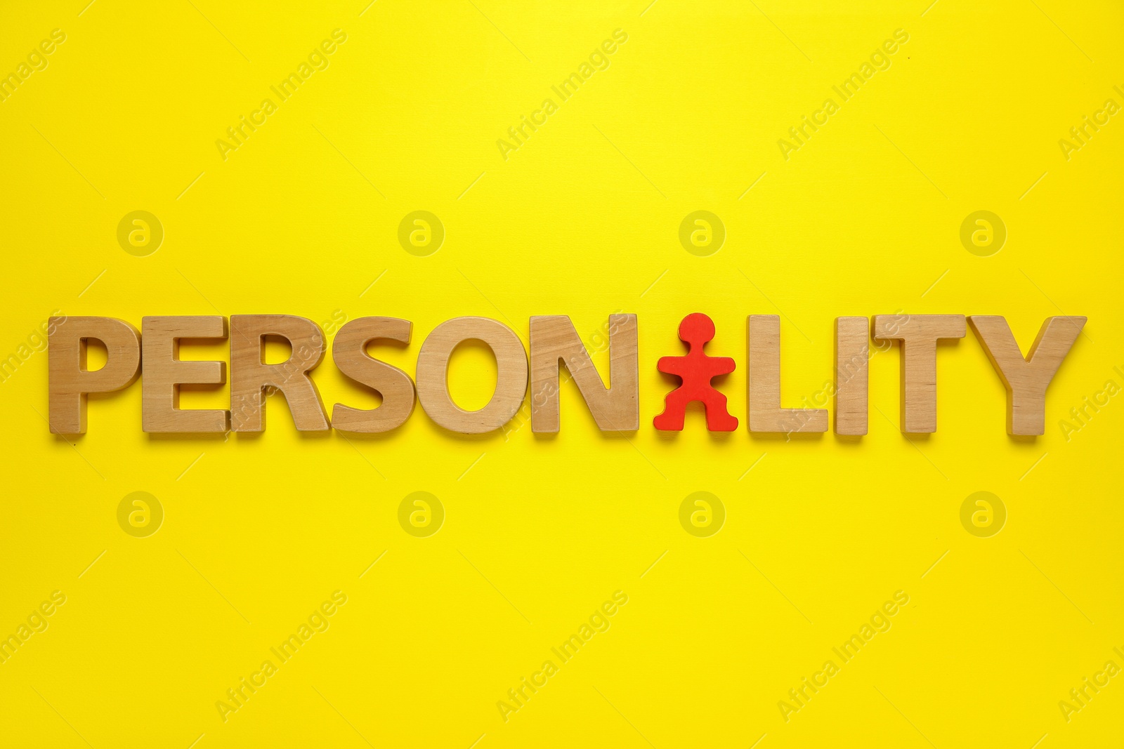 Photo of Word Personality made of wooden letters and red human figure on yellow background, top view