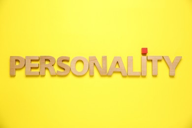 Photo of Word Personality made of wooden letters on yellow background, top view