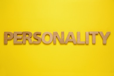 Photo of Word Personality made of wooden letters on yellow background, top view