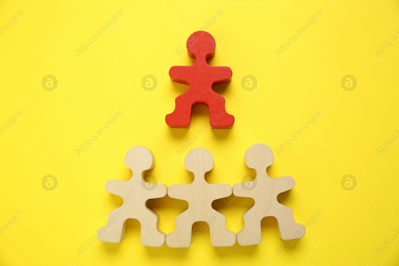 Photo of Personality test. Red human figure over wooden ones on yellow background, flat lay