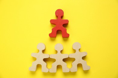 Photo of Personality test. Red human figure over wooden ones on yellow background, flat lay