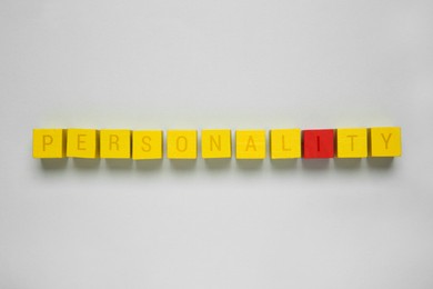 Photo of Word Personality made of cubes with letters on light grey background, top view