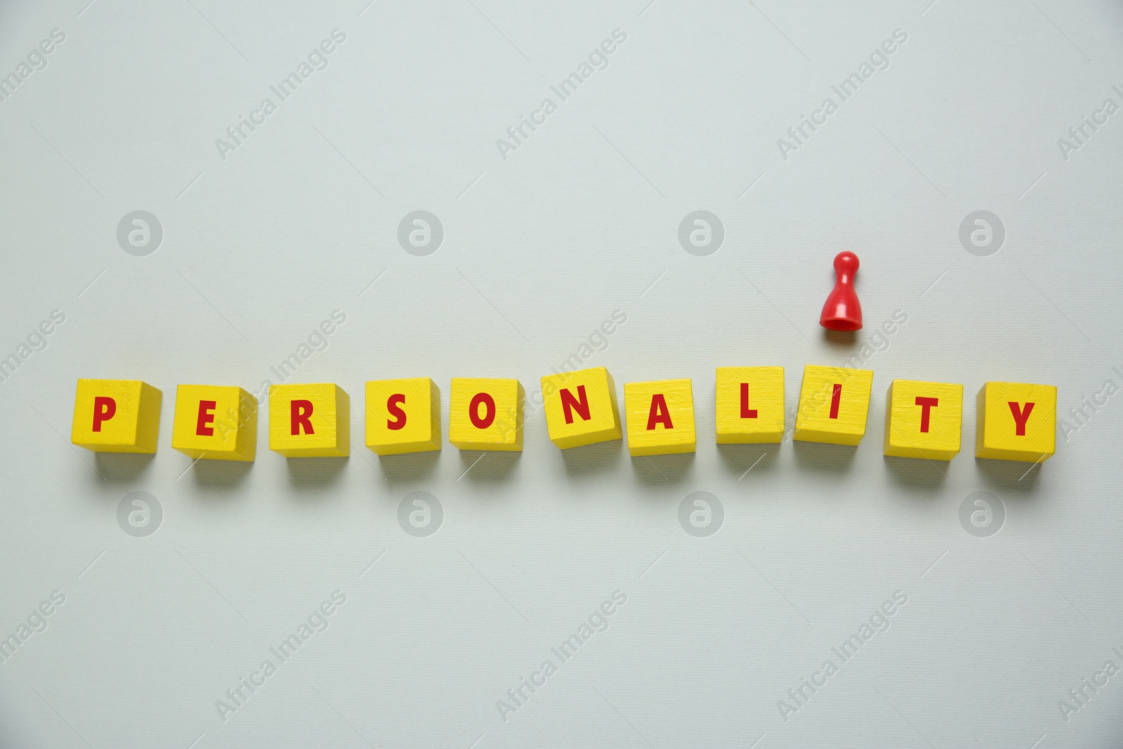 Photo of Word Personality made of cubes with letters and red game piece on light grey background, top view