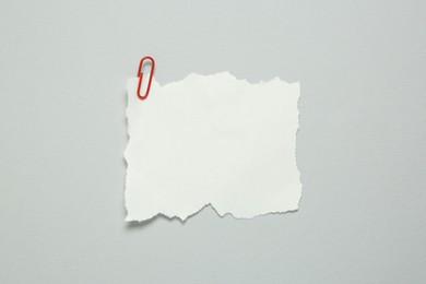 Photo of Blank note and paper clip on light grey background, top view. Space for text