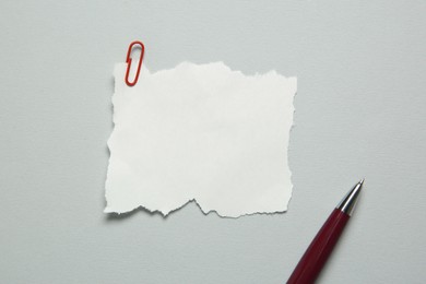 Photo of Blank note with paper clip and pen on light grey background, top view. Space for text