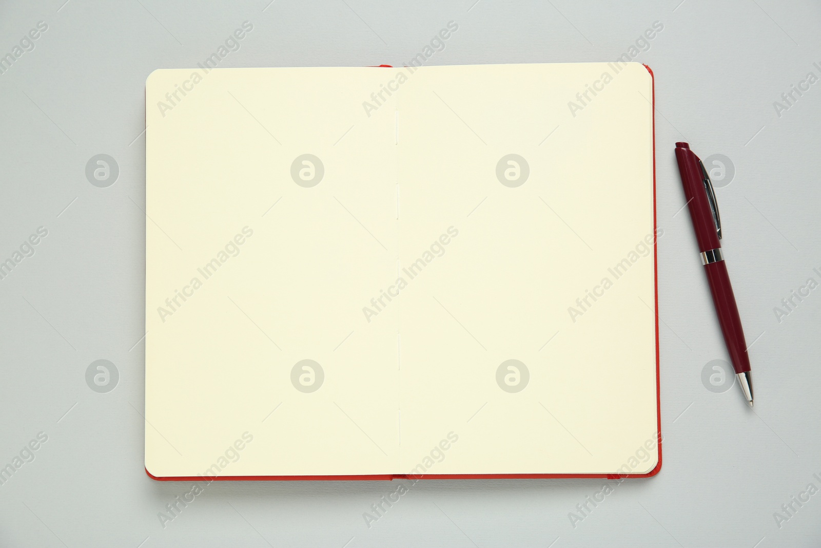 Photo of Blank notebook and pen on light grey background, top view. Space for text