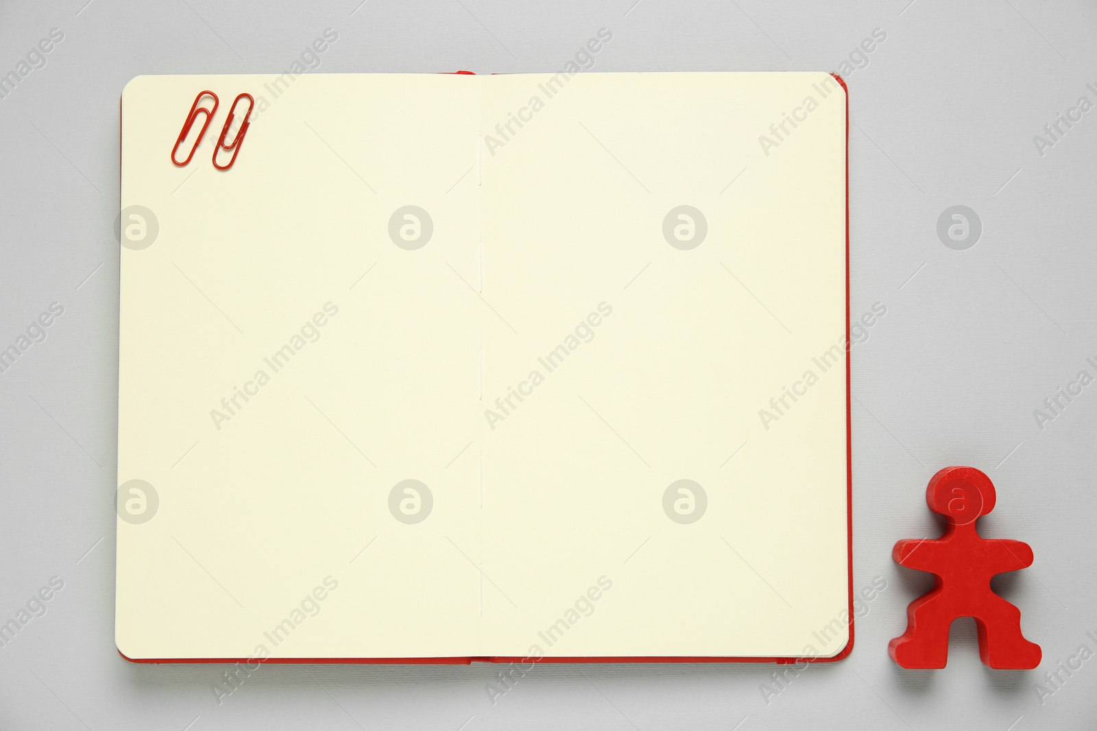 Photo of Blank notebook and human figure on light grey background, top view. Space for text