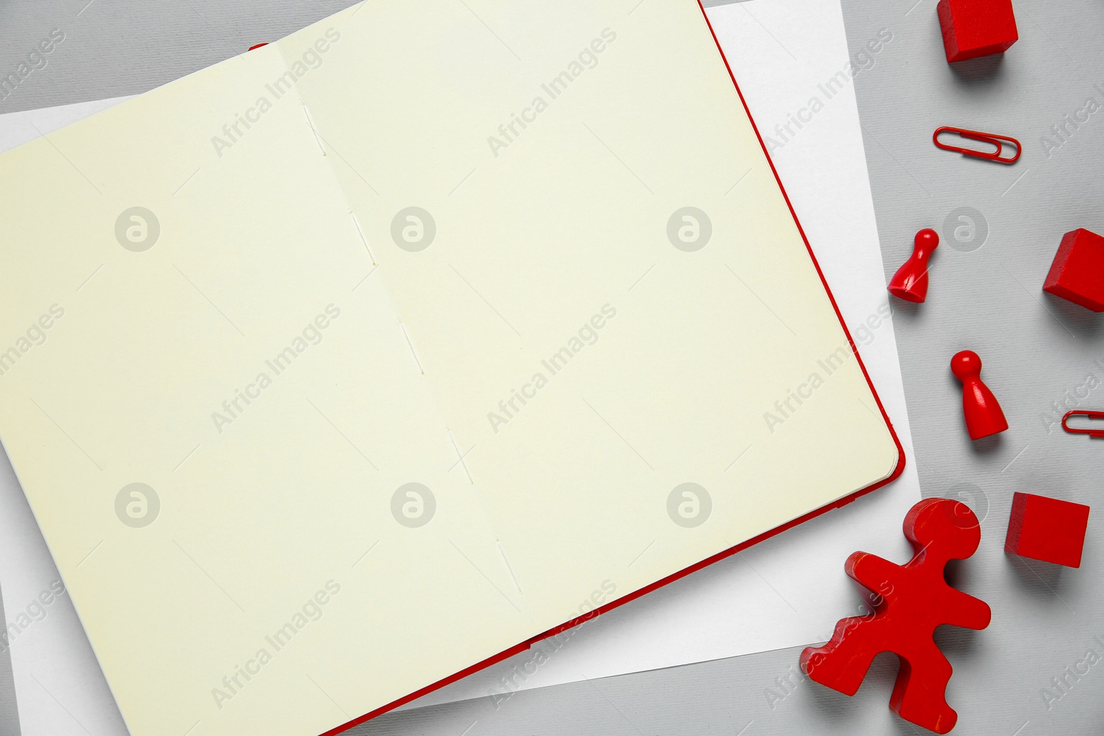 Photo of Blank notebook and human figure on light grey background, flat lay. Space for text