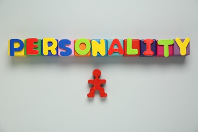 Photo of Word Personality made of colorful letters and red human figure on light grey background, top view