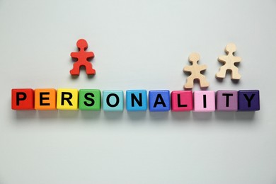 Photo of Word Personality made of colorful cubes with letters and human figures on light grey background, flat lay