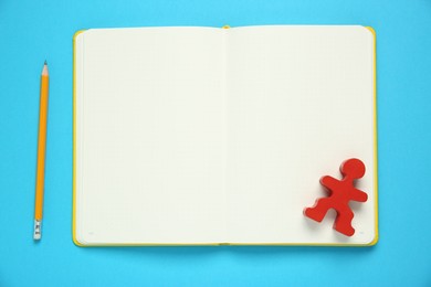 Photo of Blank notebook, human figure and pencil on light blue background, top view. Space for text