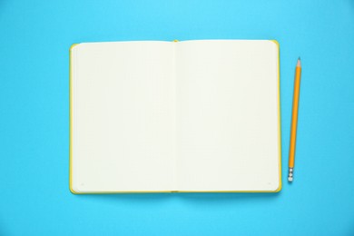 Photo of Blank notebook and pencil on light blue background, top view. Space for text