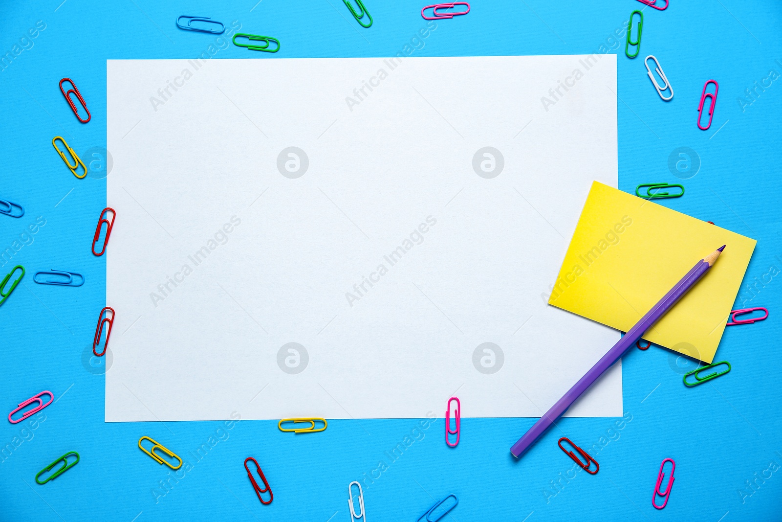 Photo of Blank sheet, pencil and paper clips on light blue background, flat lay. Space for text