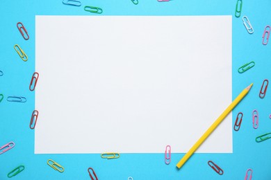 Photo of Blank sheet, pencil and paper clips on light blue background, flat lay. Space for text