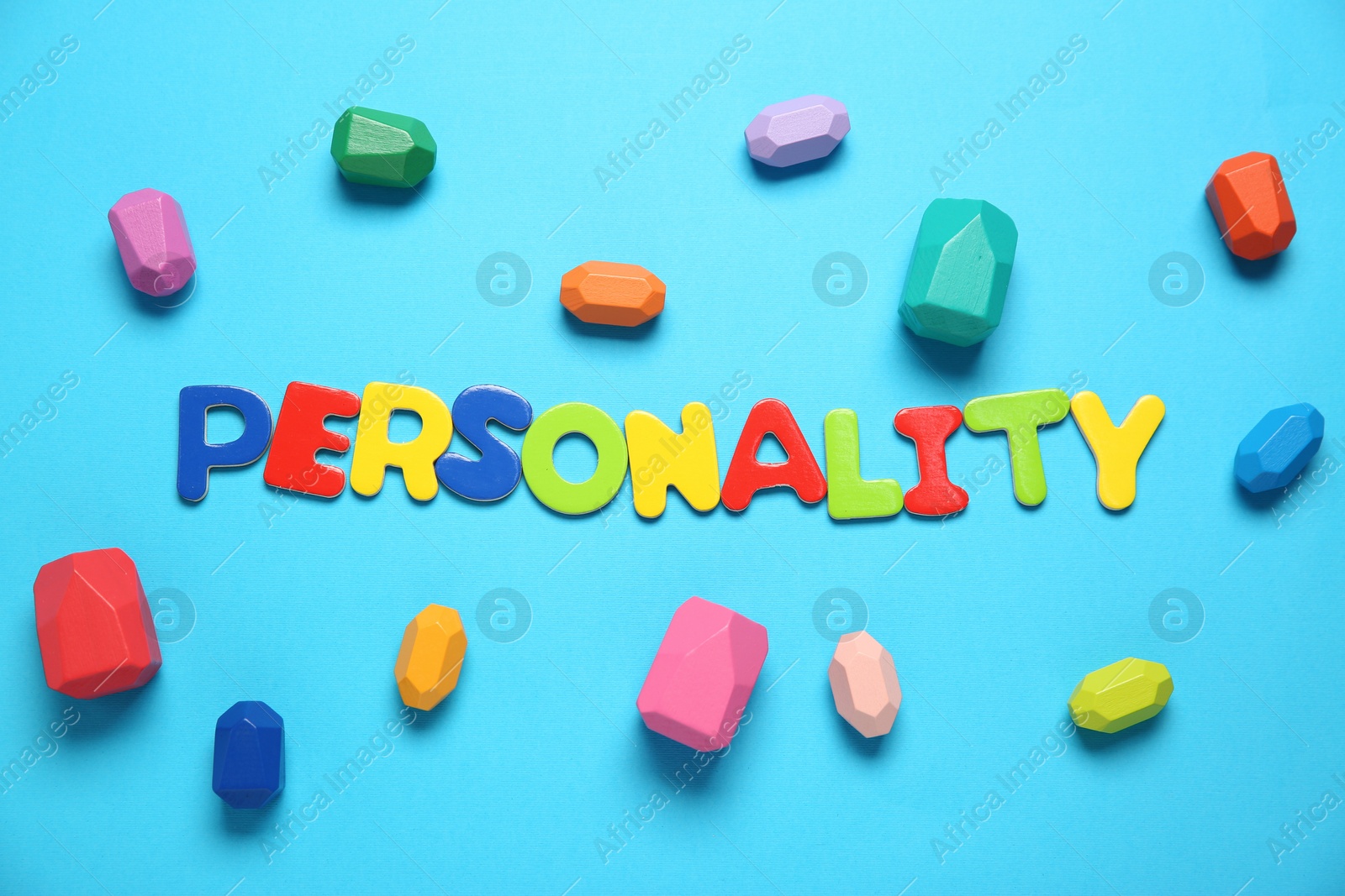 Photo of Word Personality made of colorful letters and different figures on light blue background, top view