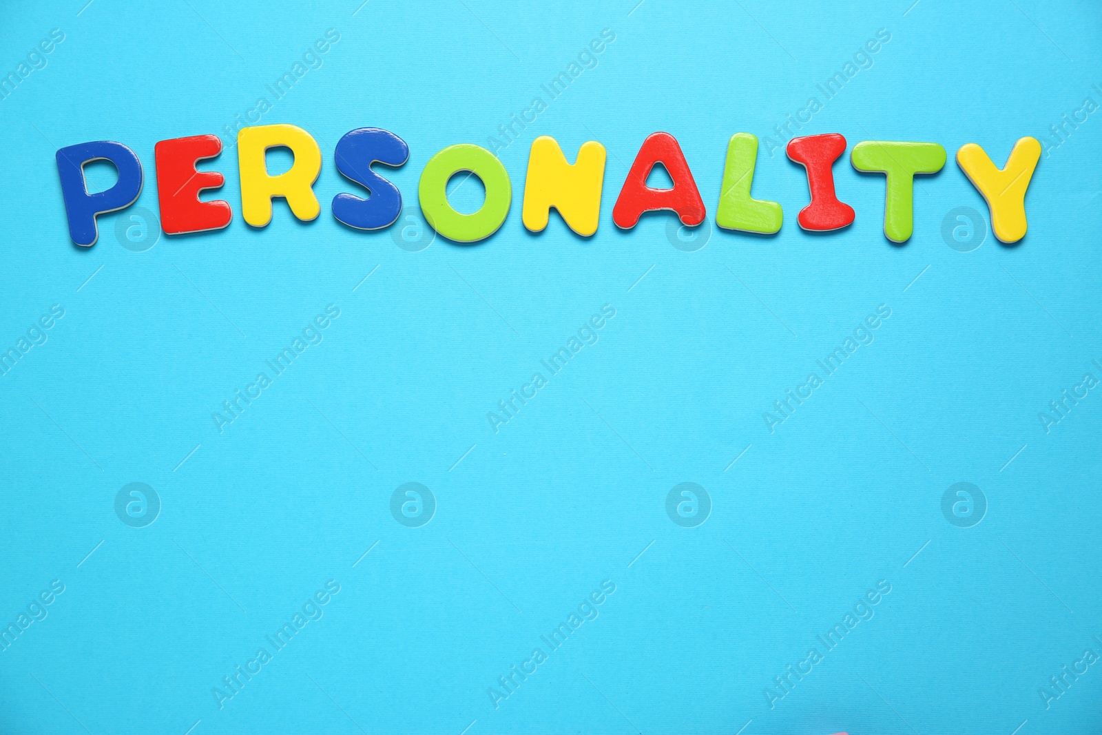 Photo of Word Personality made of colorful letters on light blue background, top view. Space for text