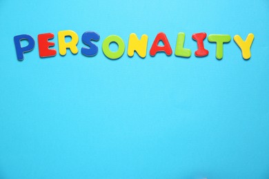 Photo of Word Personality made of colorful letters on light blue background, top view. Space for text