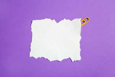 Photo of Blank note and paper clip on purple background, top view. Space for text