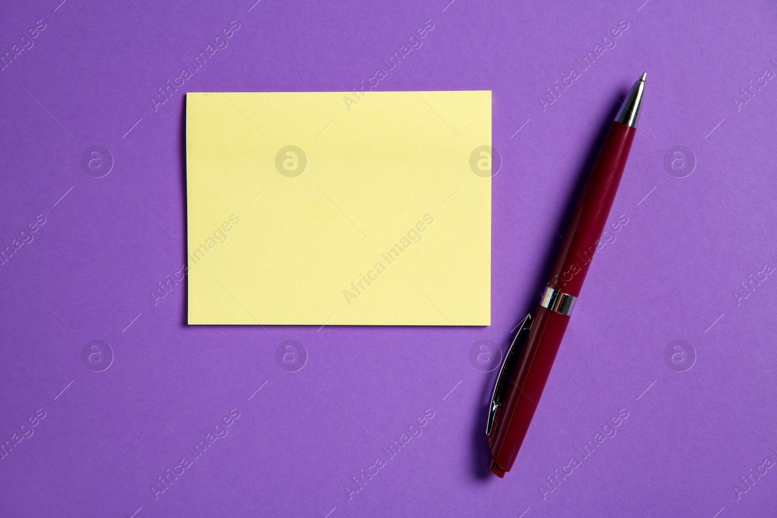 Photo of Blank note and pen on purple background, top view. Space for text