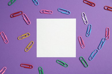 Photo of Blank note and paper clips on purple background, flat lay. Space for text