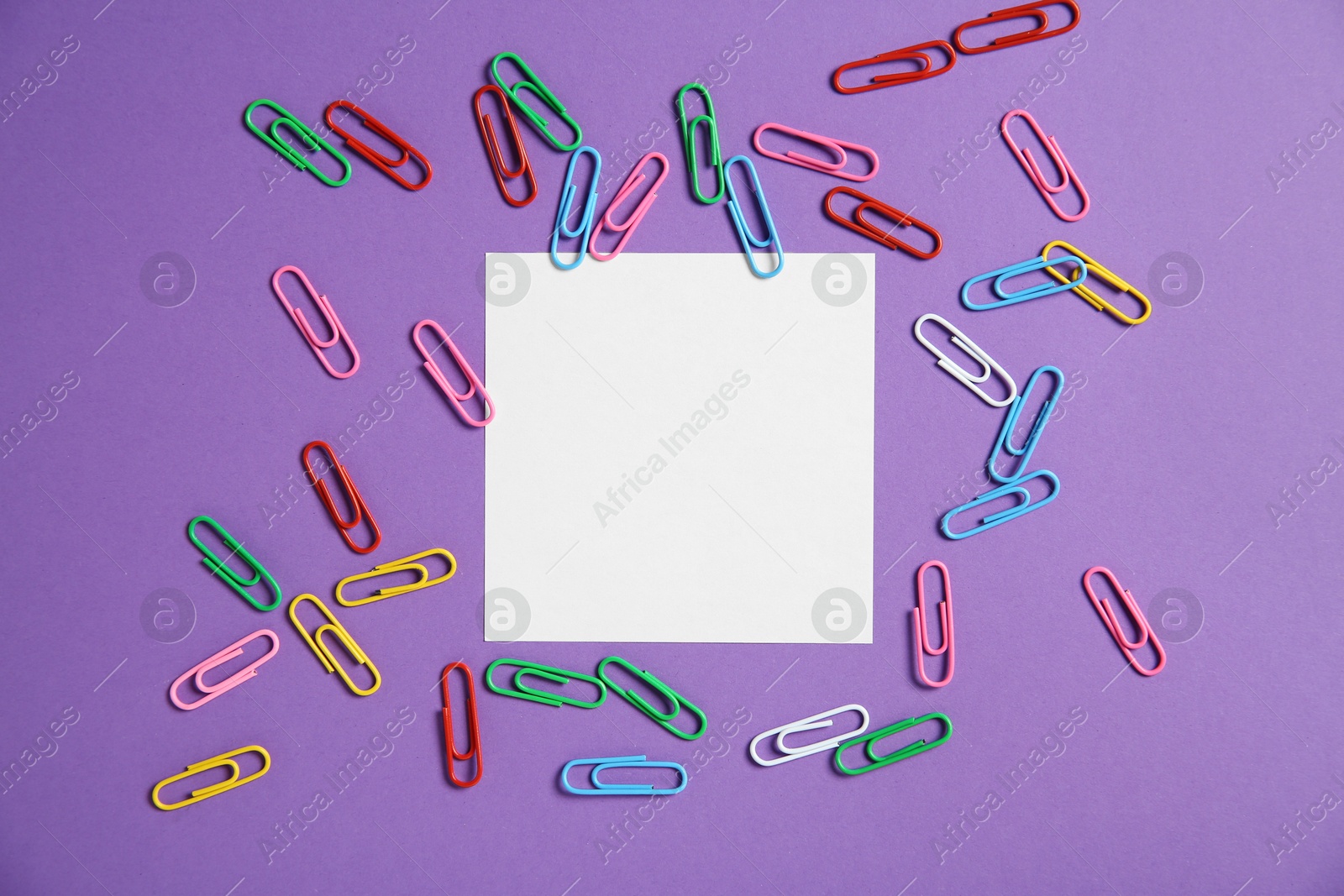 Photo of Blank note and paper clips on purple background, flat lay. Space for text