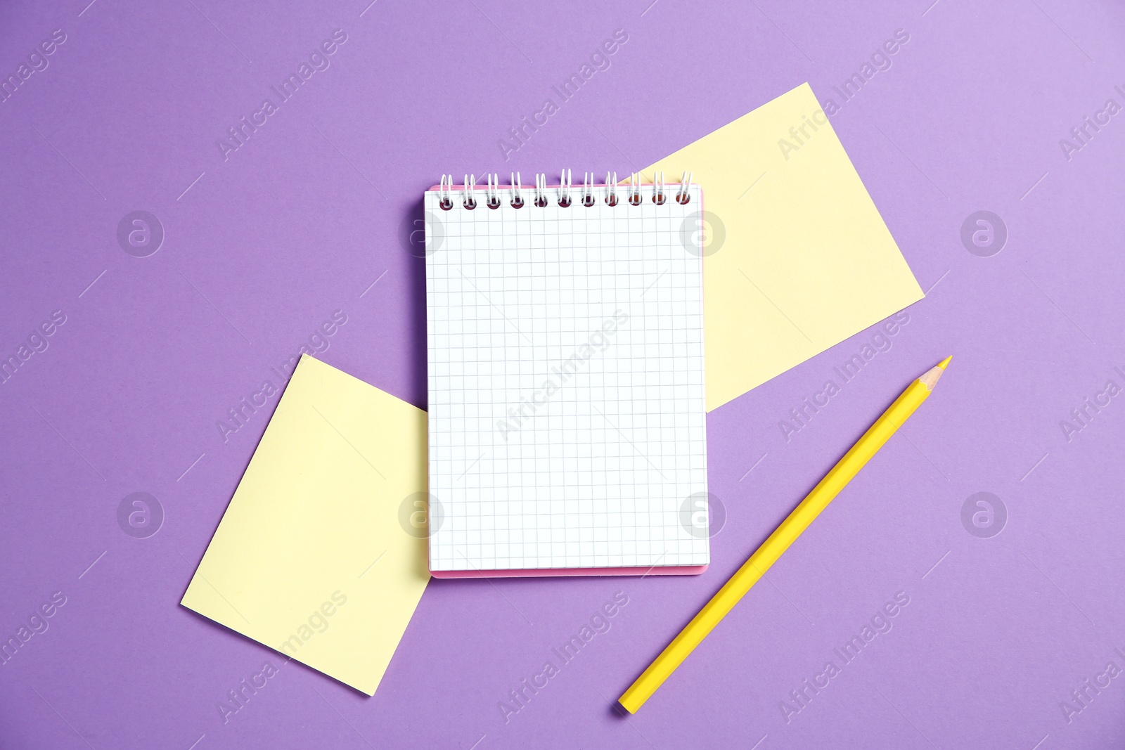 Photo of Blank notebook, paper notes and pencil on purple background, top view. Space for text