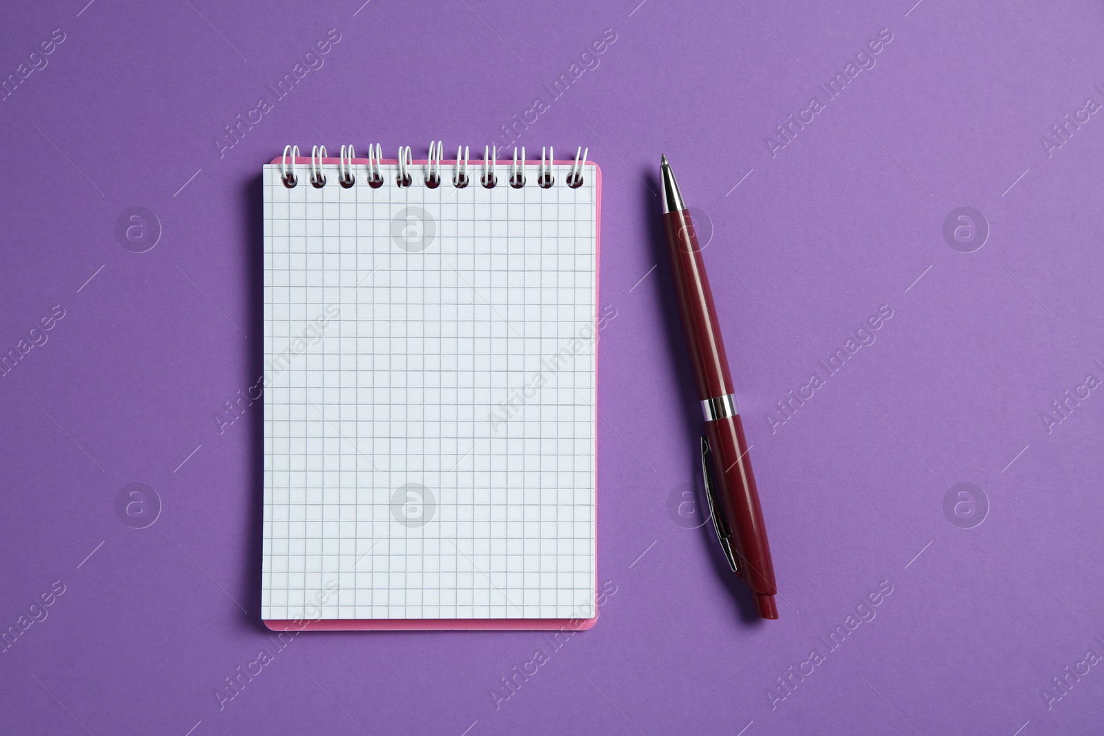 Photo of Blank notebook and pen on purple background, top view. Space for text