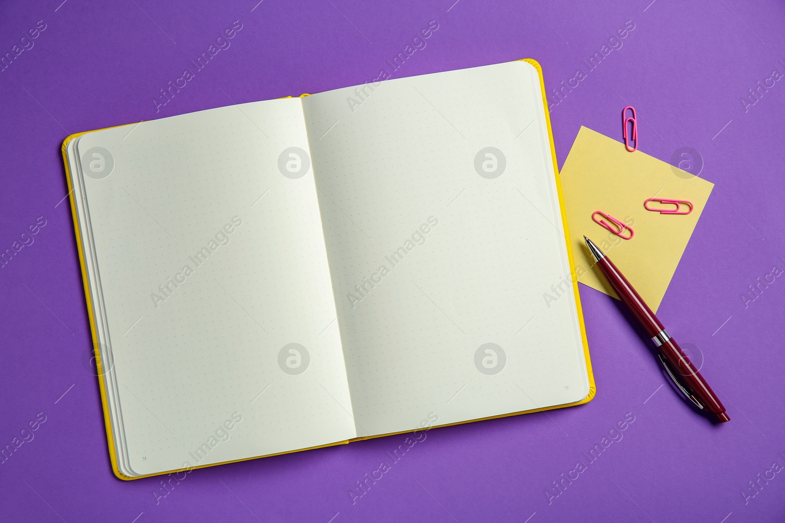 Photo of Blank notebook, note, paper clips and pen on purple background, top view. Space for text